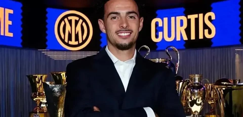 Young man in suit with trophies in background