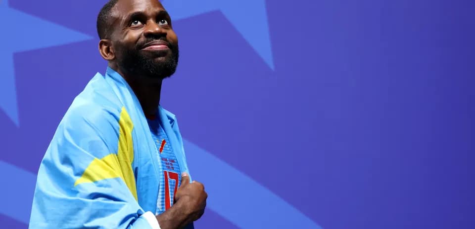 Athlete wearing flag, looking up at event backdrop