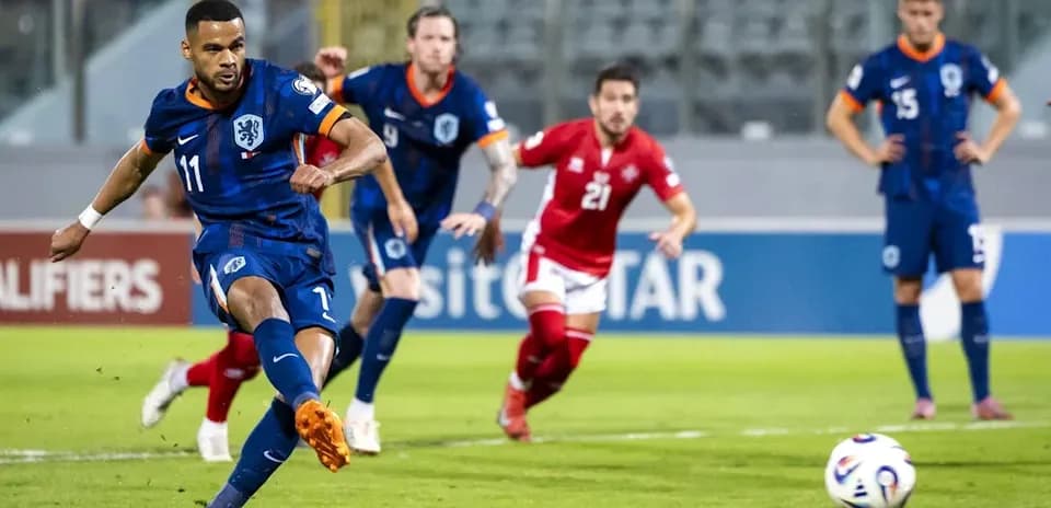 O'yinchi penalti zarbasi urmoqda, orqa fonda raqiblar