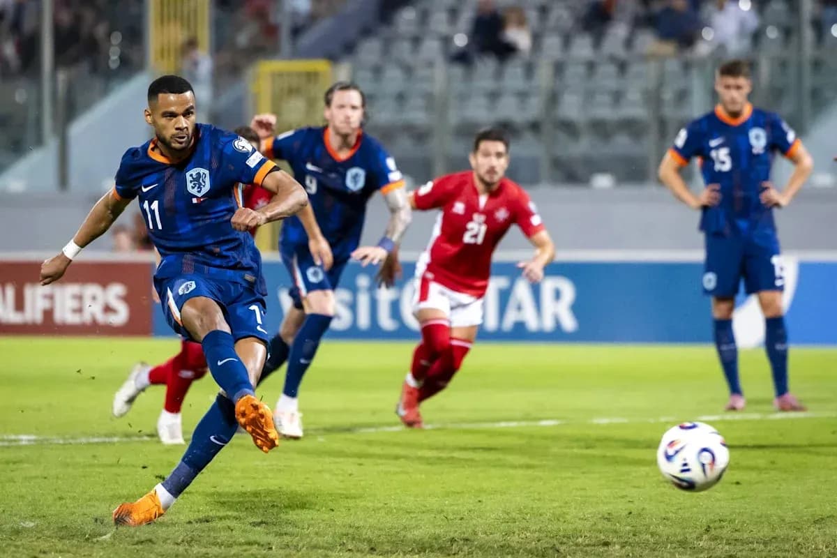 O'yinchi penalti zarbasi urmoqda, orqa fonda raqiblar
