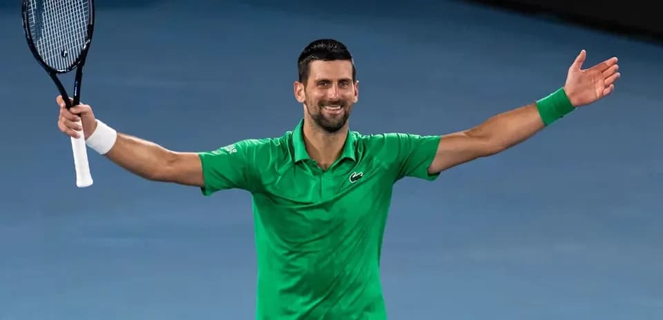 Tennis player celebrating with arms raised after match