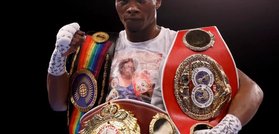 Boxer holding multiple championship belts in ring