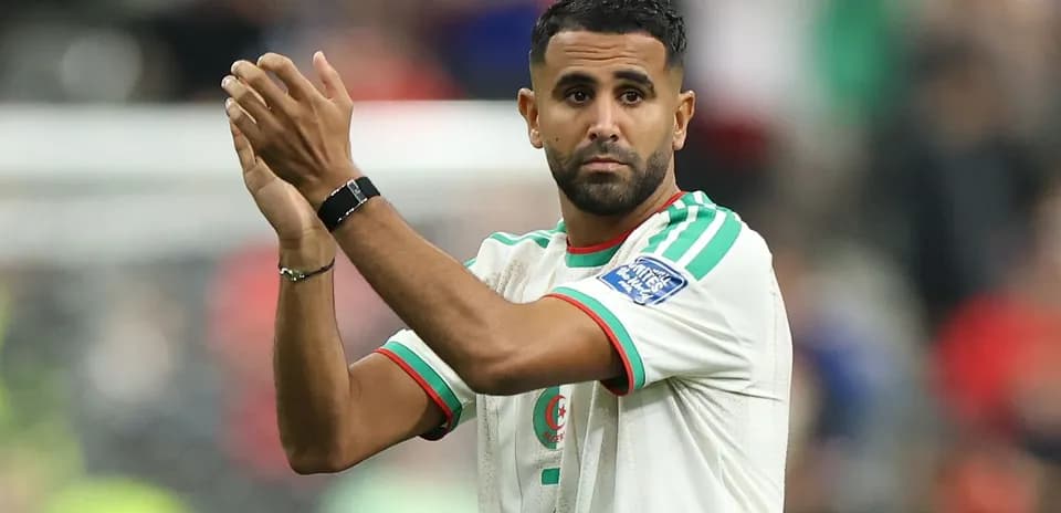 Futbolchi sahna oldida qo'llarini ko'tarib turgan