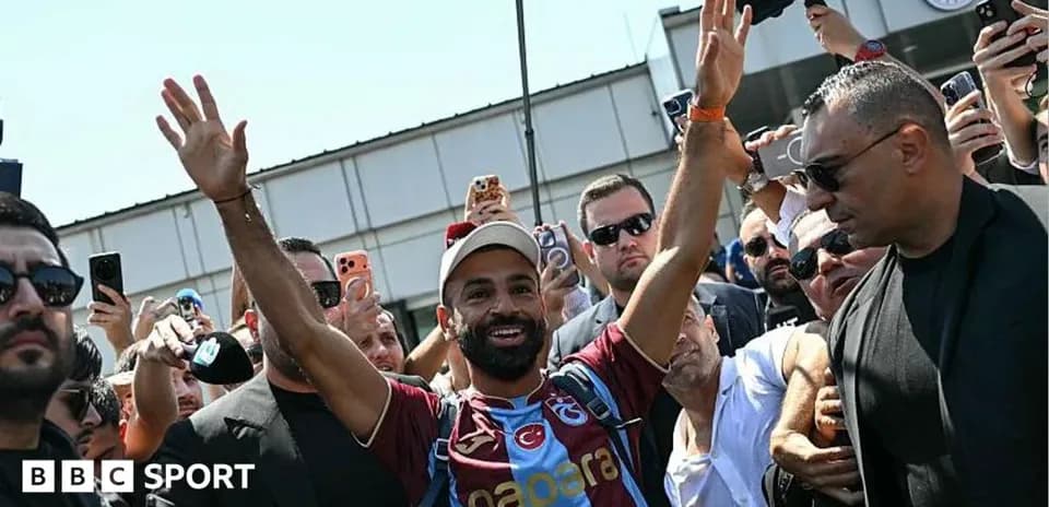 Futbolchi muxlislar oldida qo'lini ko'tarib turibdi