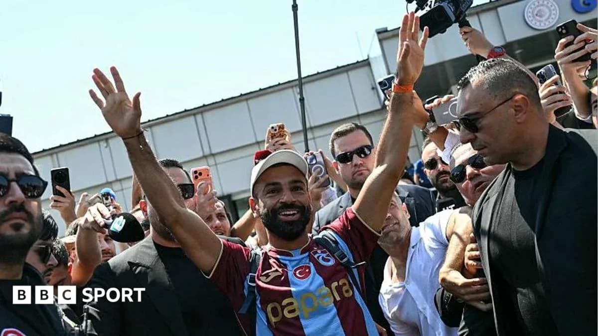 Futbolchi muxlislar oldida qo'lini ko'tarib turibdi