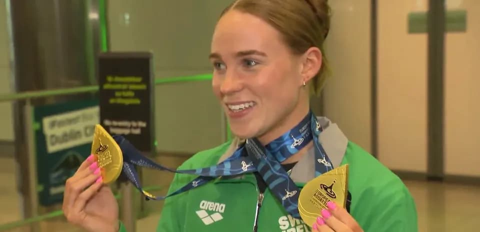 Athlete holding gold medals at airport arrival
