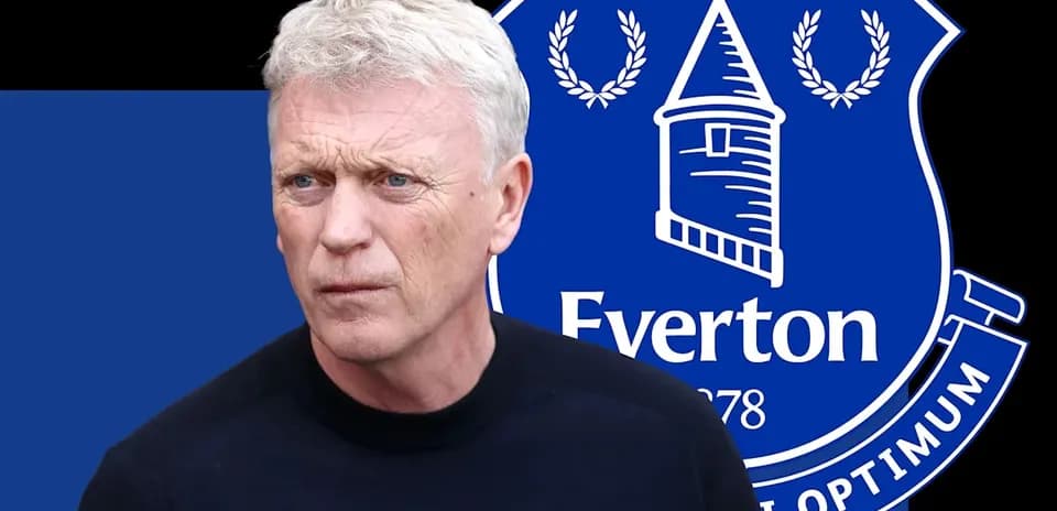 Trener Evertonning logosi oldida turibdi