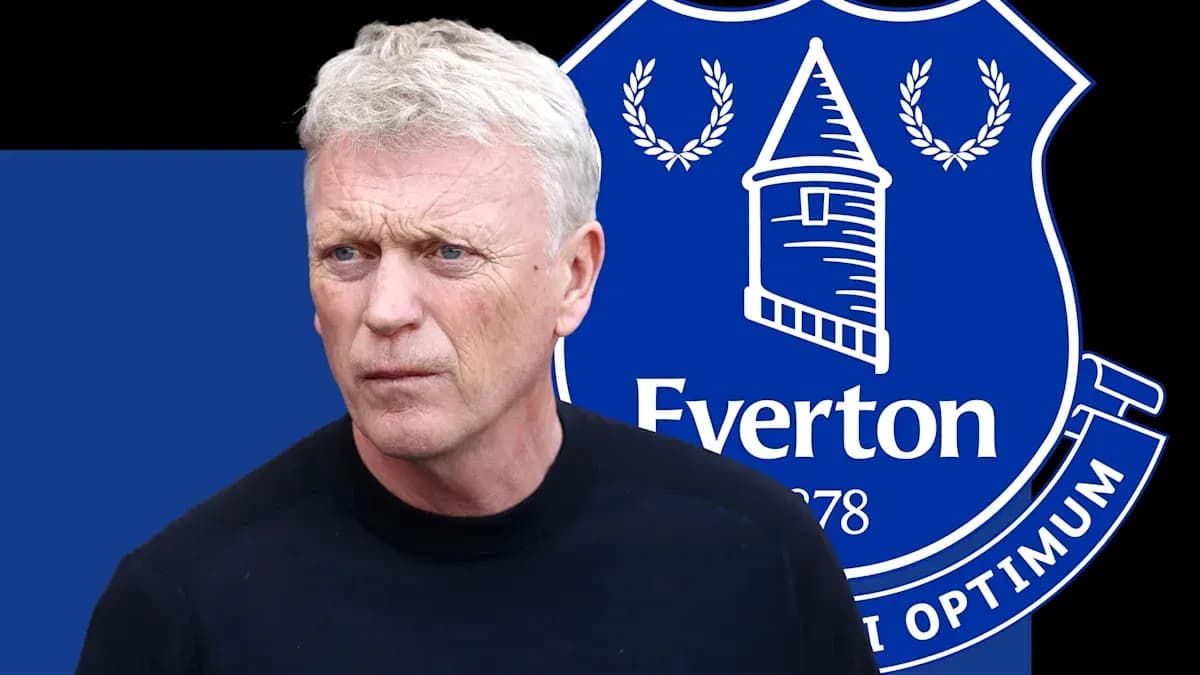 Trener Evertonning logosi oldida turibdi