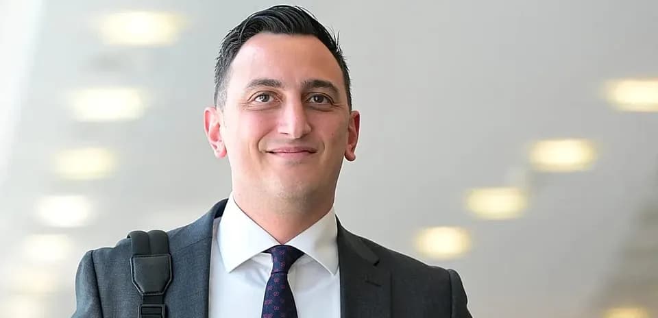 Man in suit smiling with briefcase in hallway