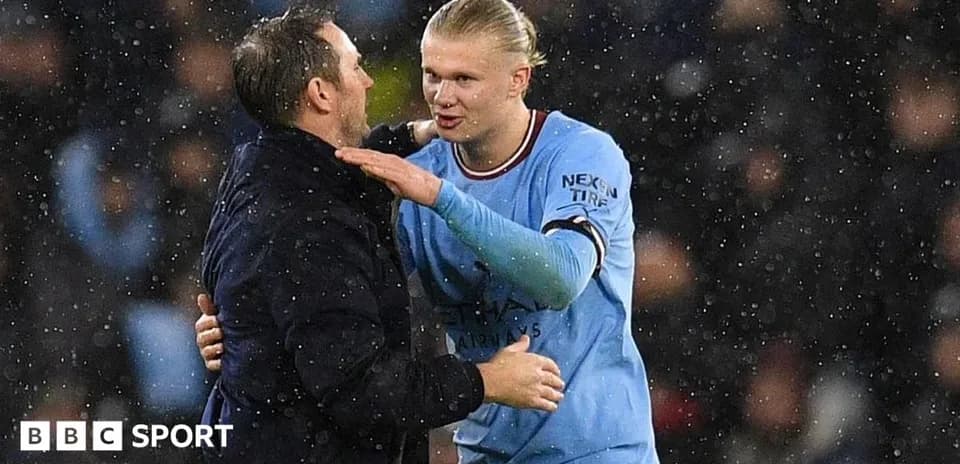 Haaland and coach interacting during rainy match