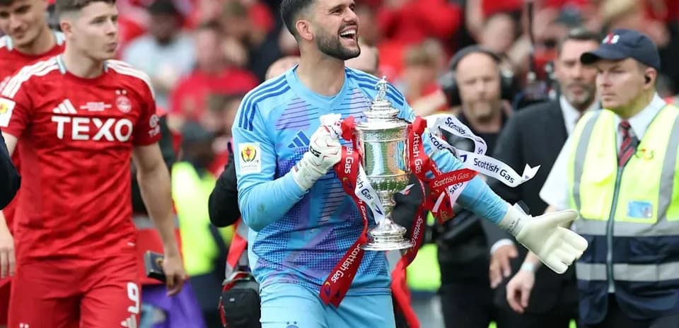 Goalkeeper celebrating with the trophy after match