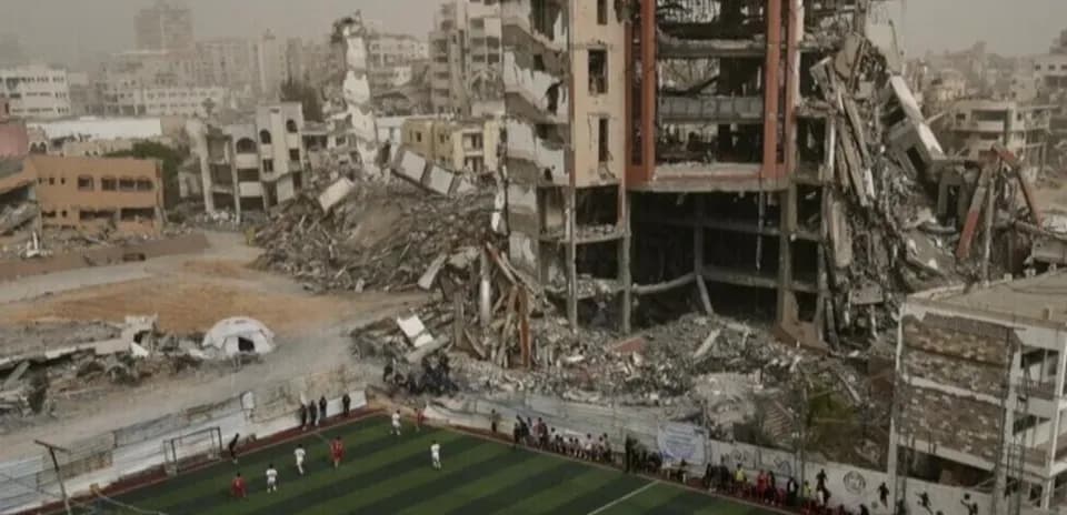 Football match in front of damaged buildings