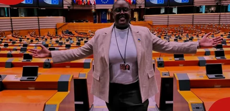 Woman standing in empty parliament chamber with arms outstretched