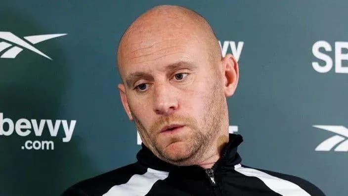 Bald man in a sports jacket at press conference