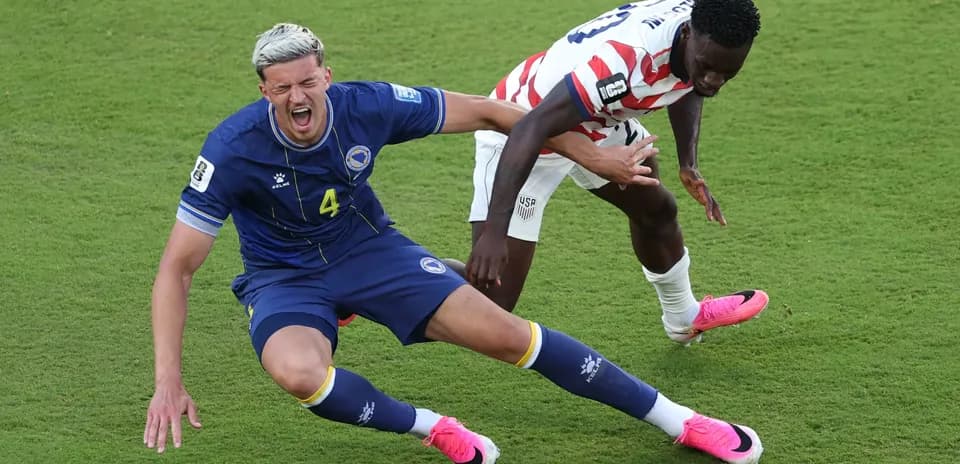 Bosnia player falls while USA player competes for ball