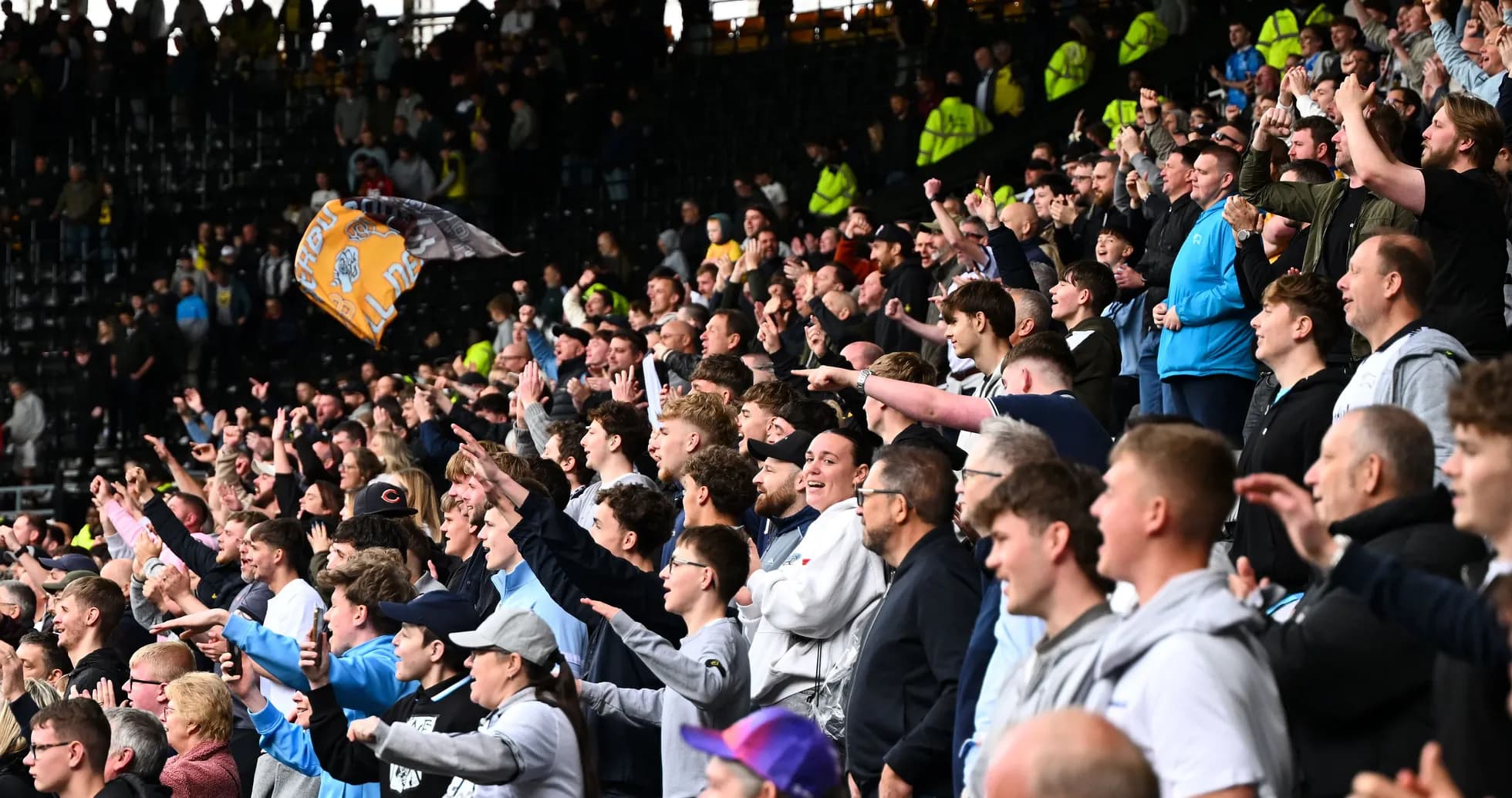 Fans cheering and waving flags in stadium stands