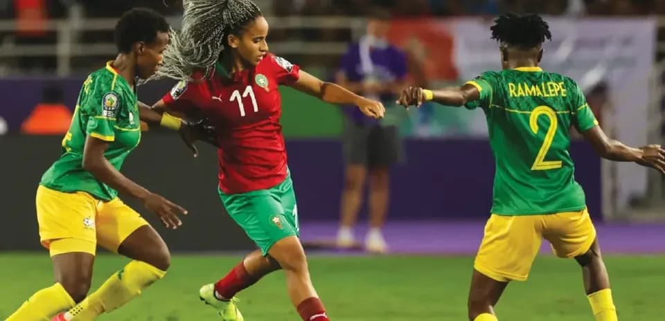 Moroccan player dribbling past two defenders during match