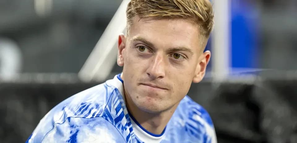 Futbolchi benchda o'tirgan holda tasvirlangan