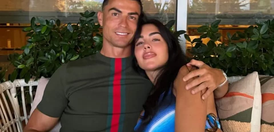 Couple posing together on a couch surrounded by plants