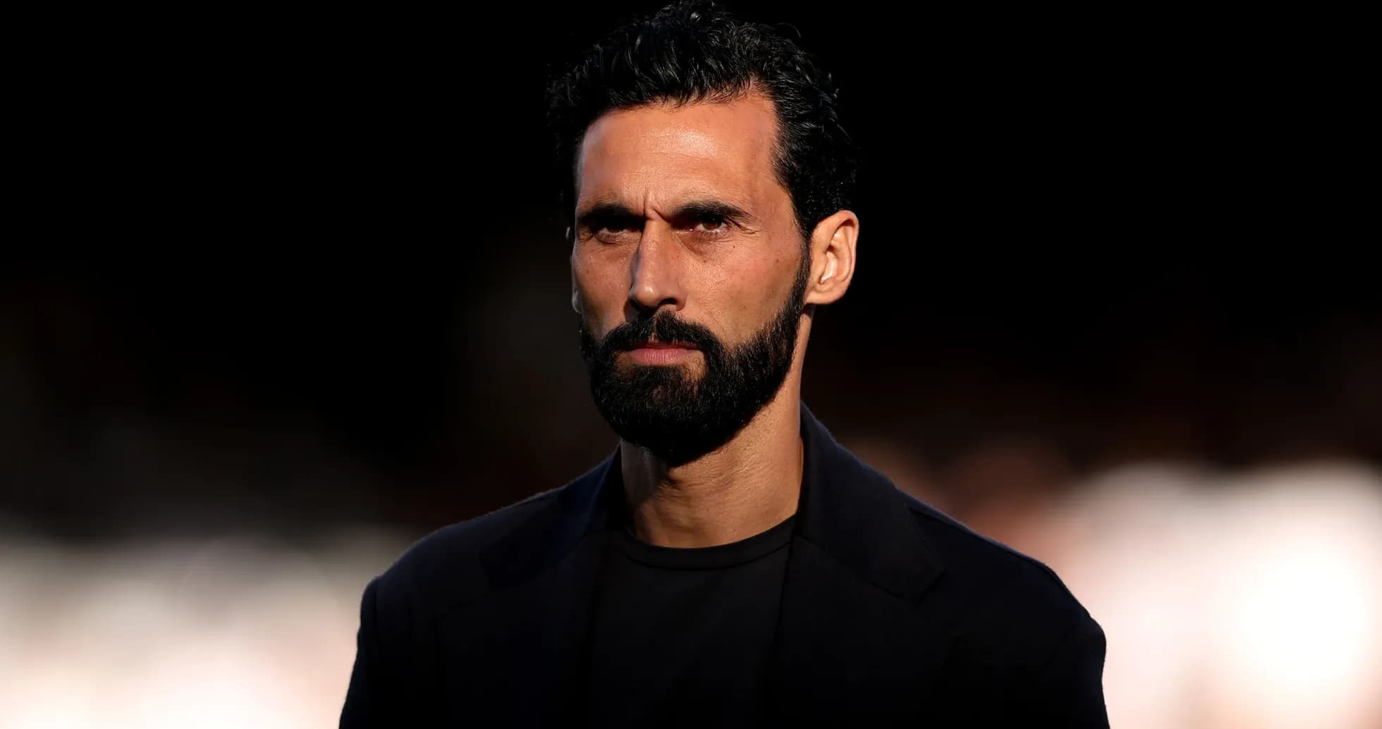 Man with beard and serious expression in dark setting