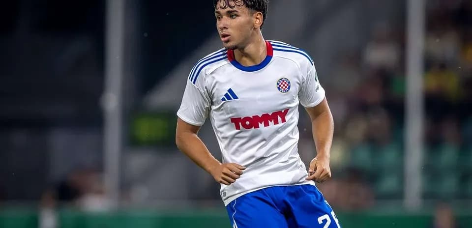 Futbolchi maydonda harakatda, tomoshabinlar ortida