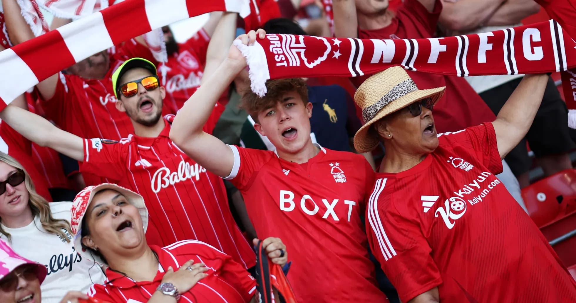 Fans in red jerseys cheering at a football match