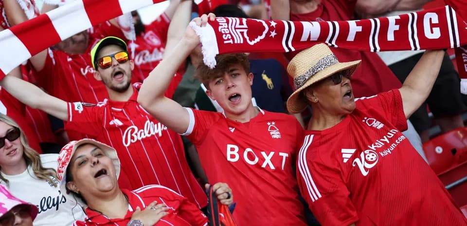 Fans in red jerseys cheering at a football match