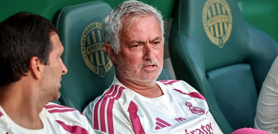 Mourinho sitting on bench with teammate during match