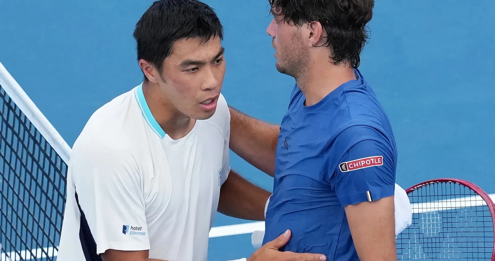 Two tennis players shaking hands at net