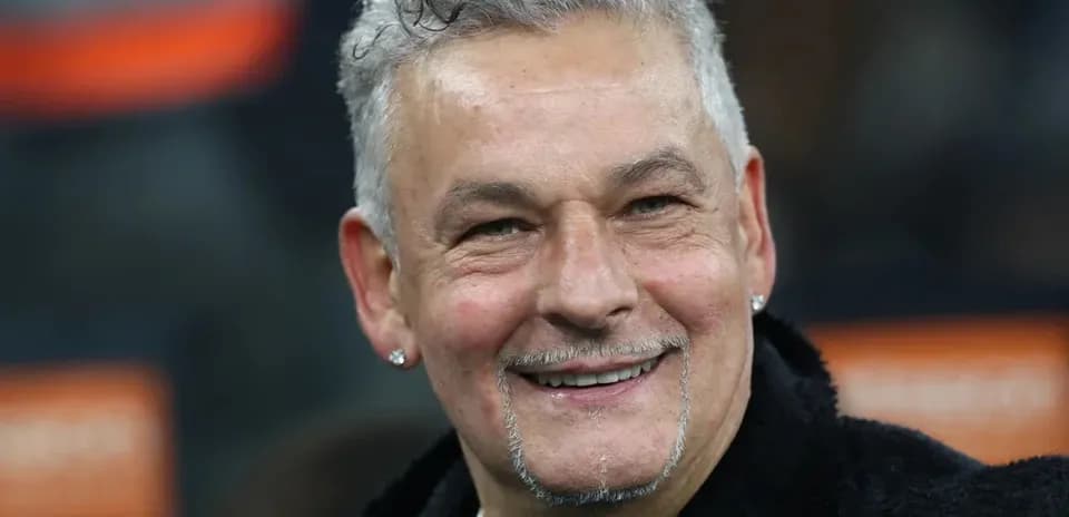 Man smiling with curly hair and earrings