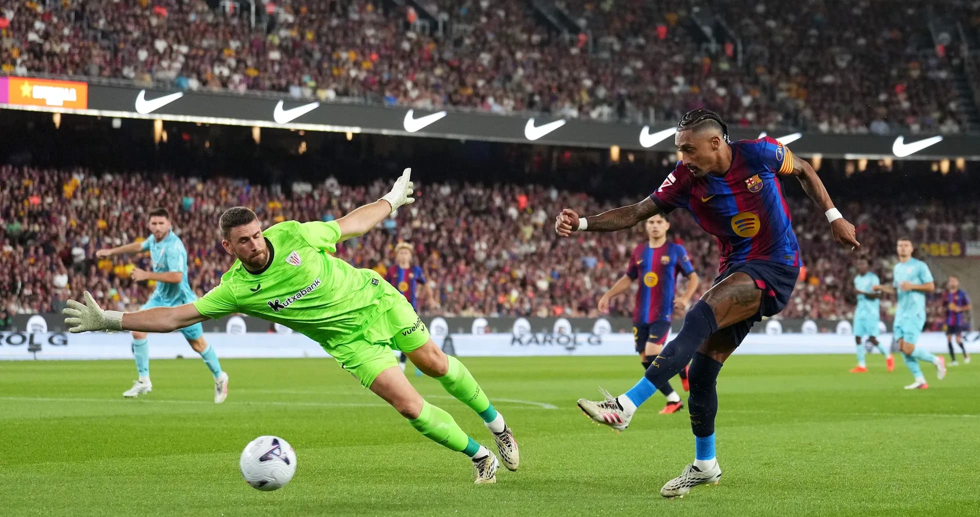 Barcelona player shooting while goalkeeper attempts save