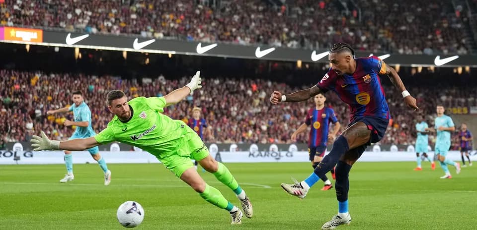 Barcelona player shooting while goalkeeper attempts save
