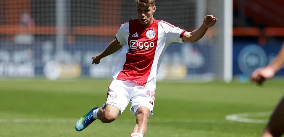 Futbolchi Ajax formasida to'pni urayotgan paytda