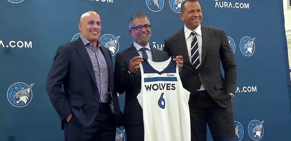 Three men presenting a Minnesota Wolves jersey
