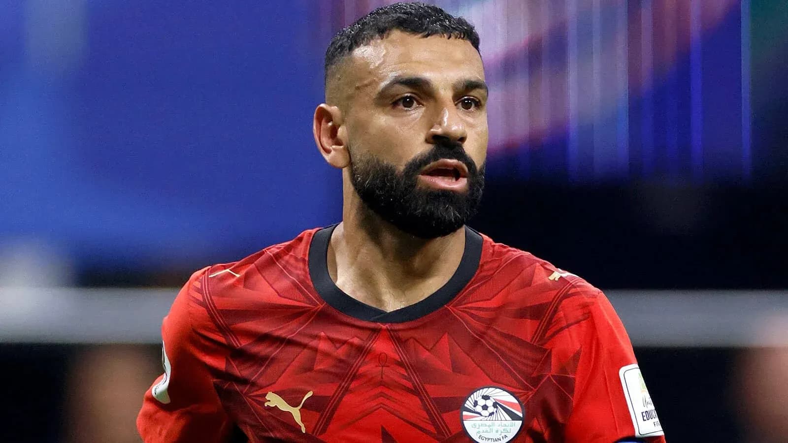 Futbolchi qizil futbolka kiygan, harakatda
