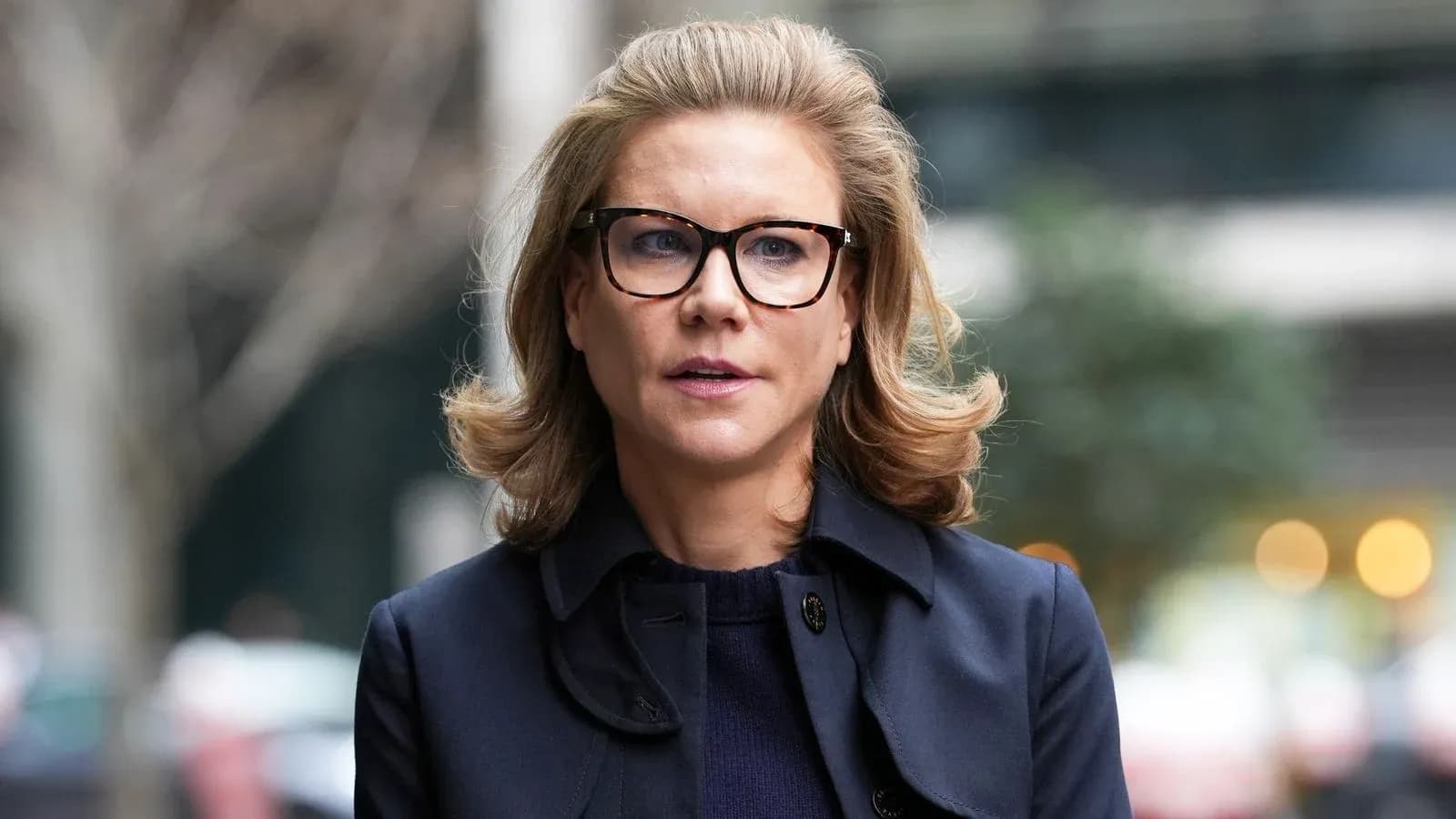 Woman wearing glasses walking outdoors in city