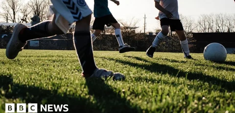 Bolalar futbol maydonida to'p bilan o'ynashmoqda