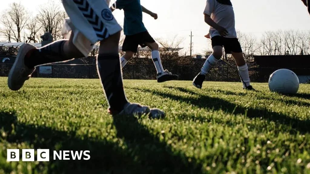 Bolalar futbol maydonida to'p bilan o'ynashmoqda