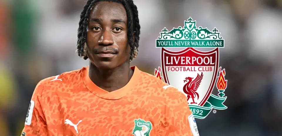 Goalkeeper in orange jersey with Liverpool logo background