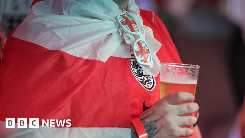 Fan wearing England flag and holding beer