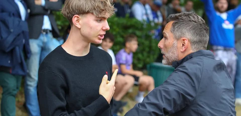 Young man speaking with adult in crowd