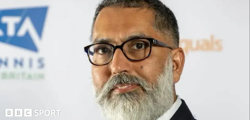 Man with glasses and beard in front of logo