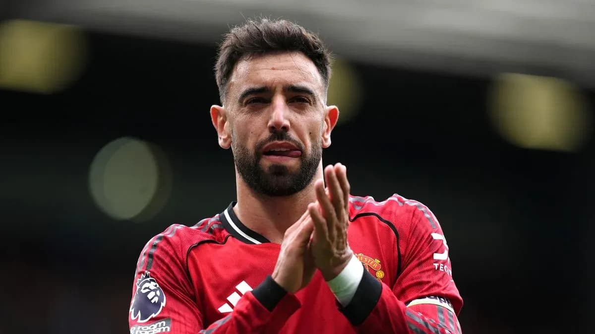 Futbolchi qizil formada maydonda qo'lni qizg'ich bilan bosmoqda