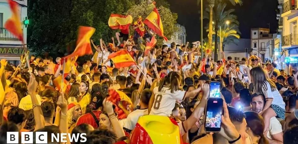 Celebration with fans waving Spanish flags at night