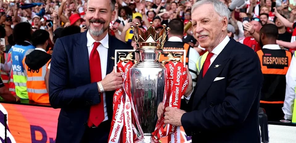 Two officials holding Premier League trophy with fans