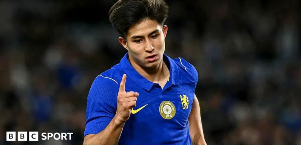 Futbolchi bir qo'lini ko'tarib, g'alaba belgisini ko'rsatmoqda