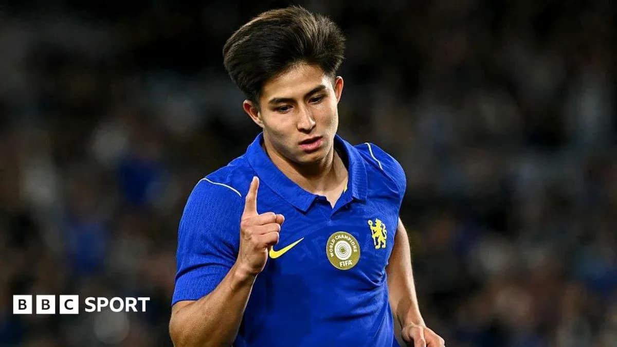 Futbolchi bir qo'lini ko'tarib, g'alaba belgisini ko'rsatmoqda