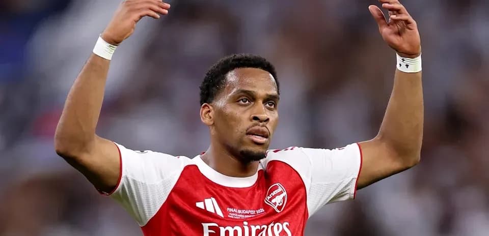 Futbolchi Arsenal formasida maydonda qo'llarini ko'tarib turibdi