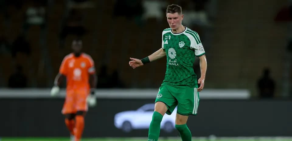 Futbolchi yashil forma kiygan, to'p bilan harakatda