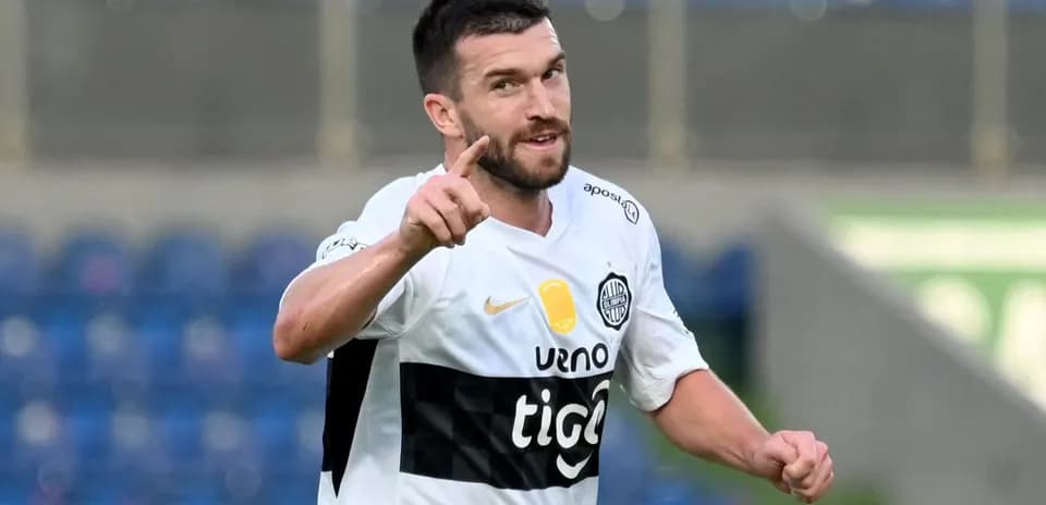 Futbolchi gol urib, qo'lini ko'tarib turibdi